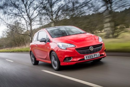 Red Vauxhall Corsa driving with woodland in background