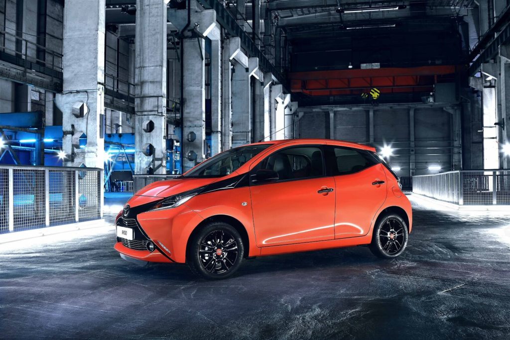 Orange and black Toyota Aygo in a warehouse at night