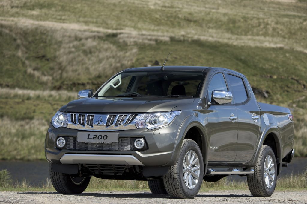 Grey Mitsubishi L200 off road with mountains in the background