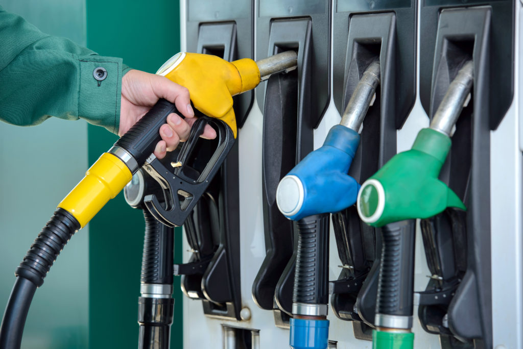 petrol pumps of different colours with a person in a green suit holding one of the pumps