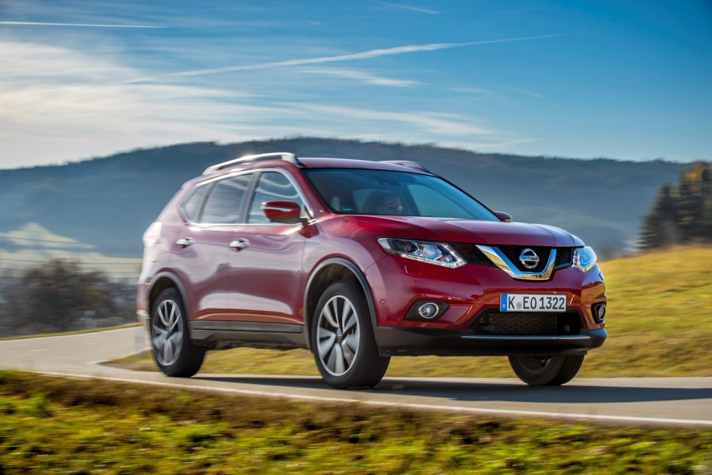 Red Nissan X-Trail driving on country road