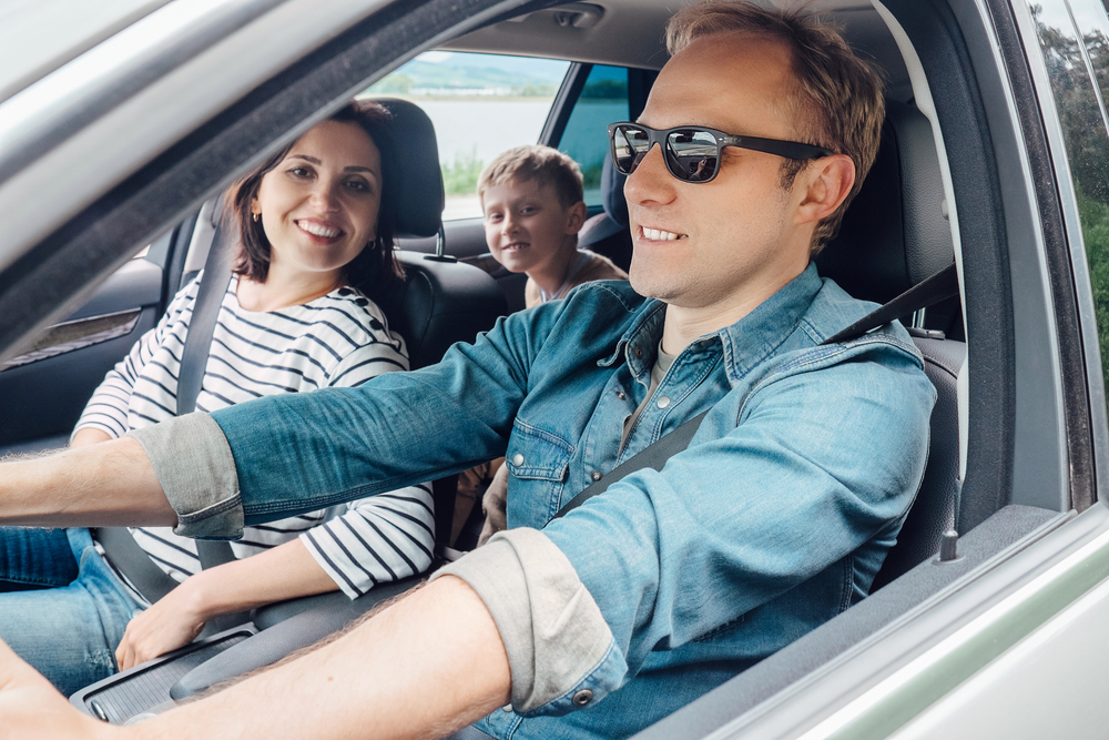 family in a car smiling with man wearing a denim shirt and sunglasses