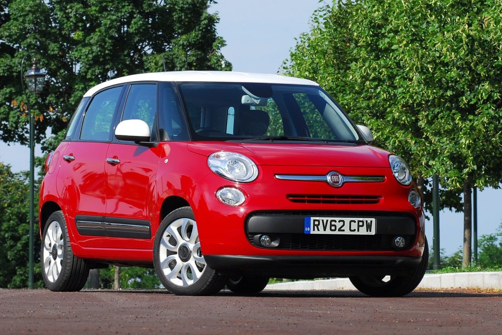 red fiat 500l parked on road in front of rows of green trees