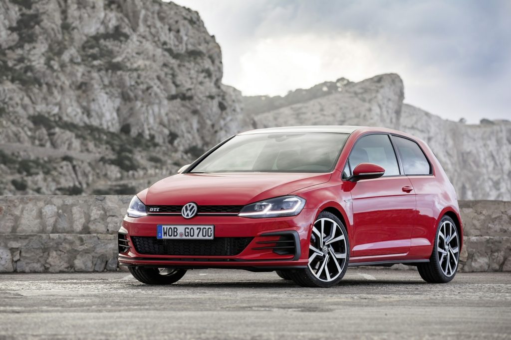 a red Volkswagen Golf next to some cliffs