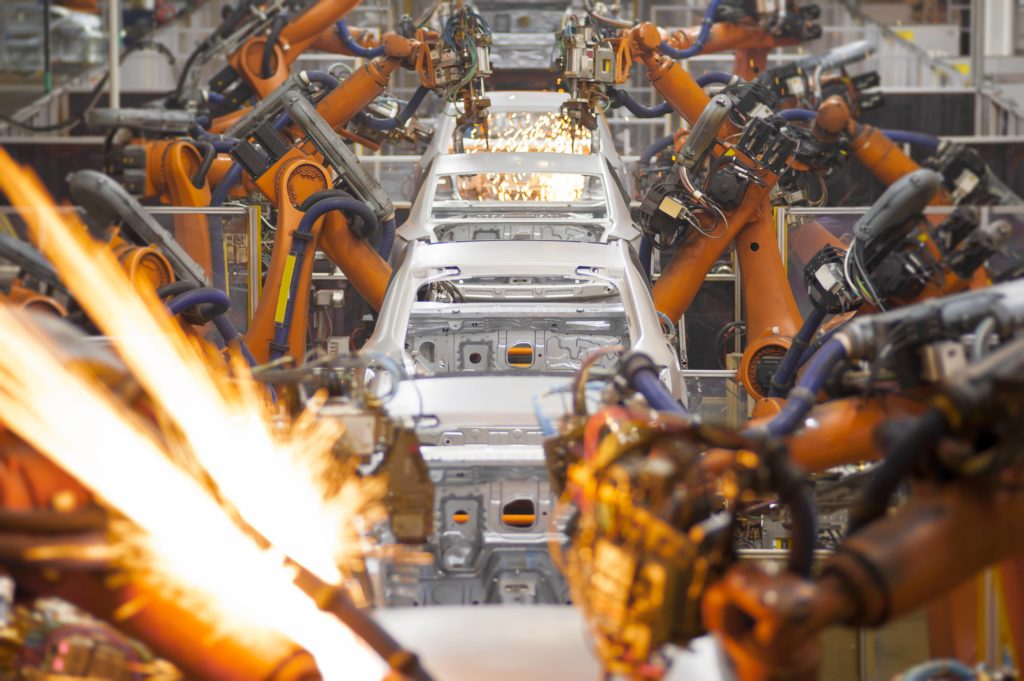 car on the assembly line with orange robots sparking in the for front