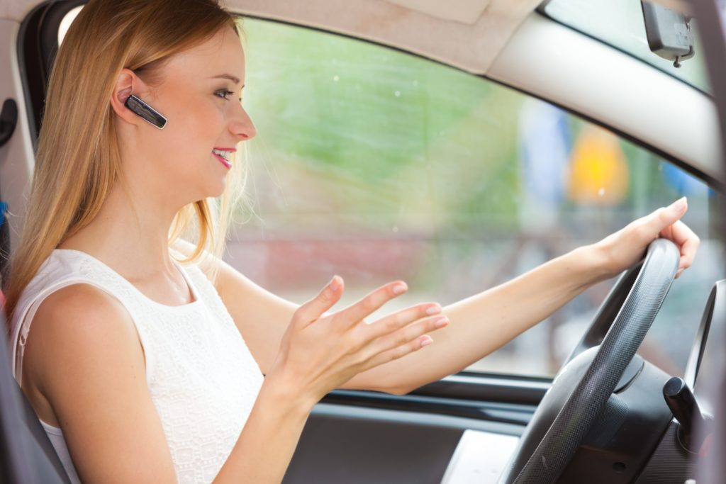 blond women talking on the phone via Bluetooth headset whilst driving