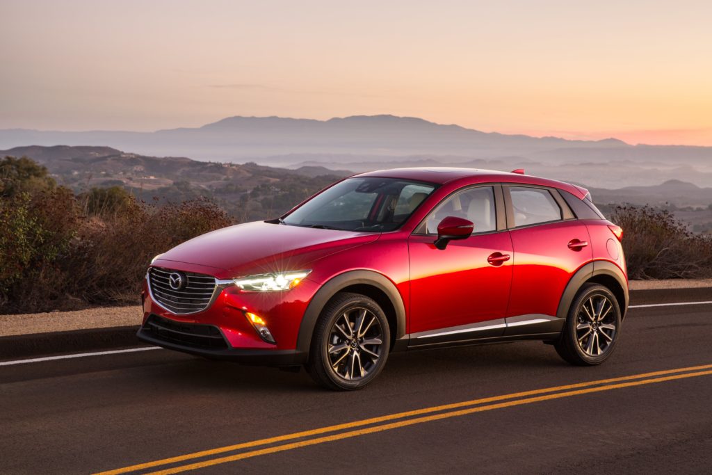 a red mazda cx-3 hatchback driving down desert road