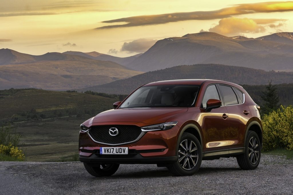 dark coloured mazda cx5 in front of some mountains at sun set