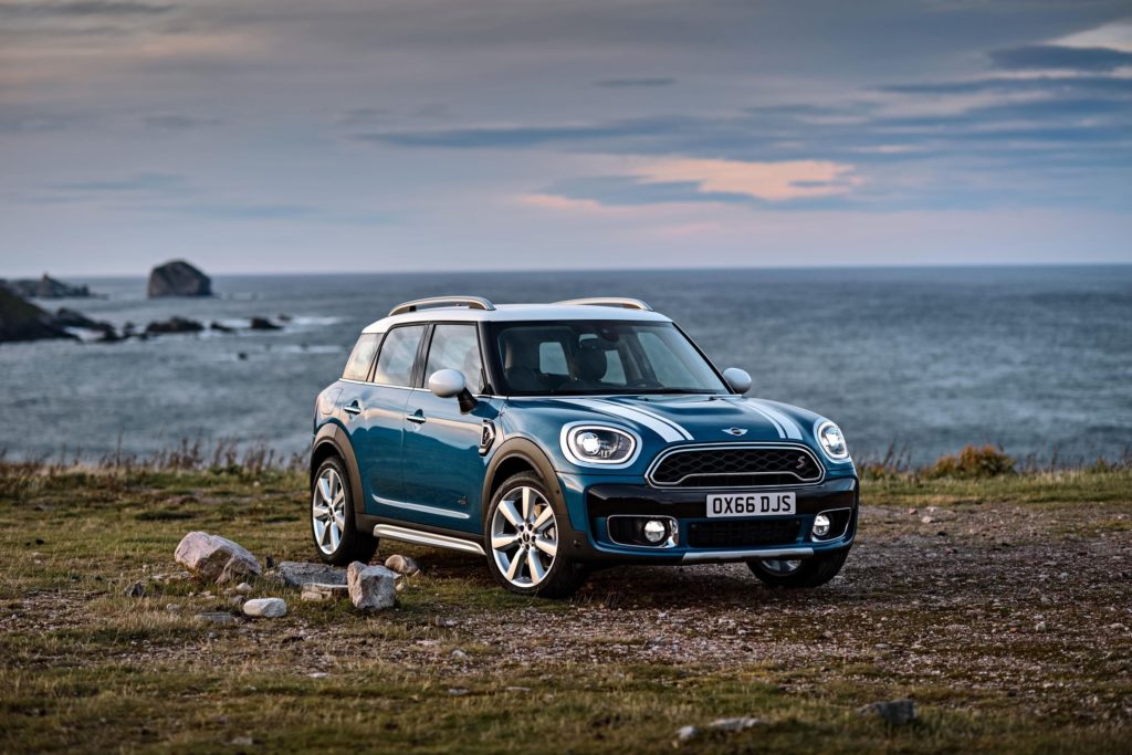 metallic blue mini countryman hatchback parked on grassy and rocky hills with the sea in the background