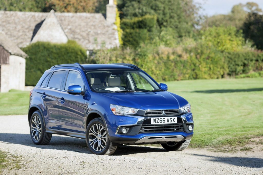 Blue Mitsubishi ASX parked on a country road with a country house in the background