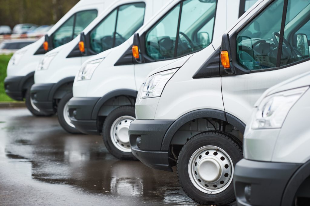 Row of white vans in van dealership courtyard