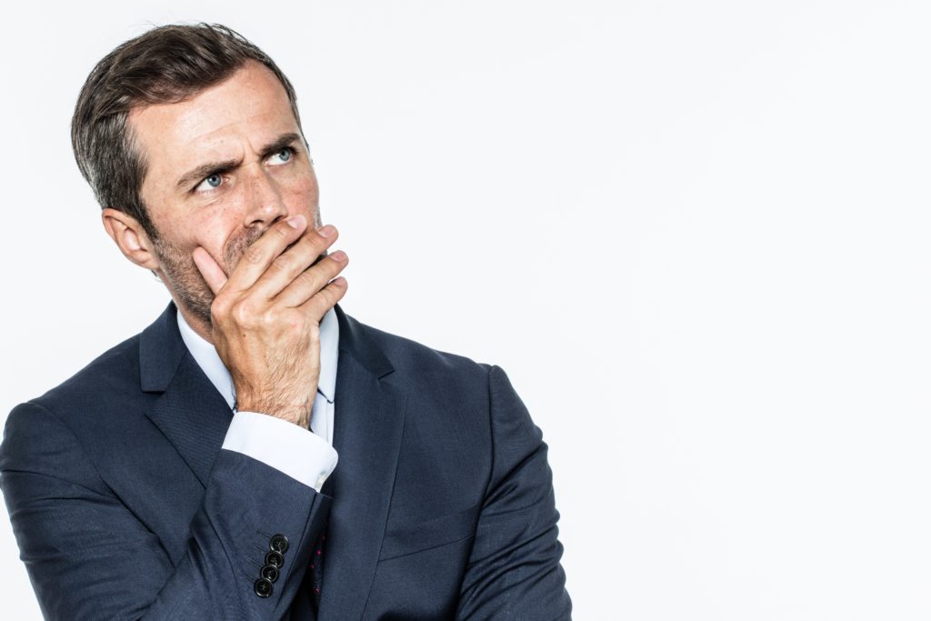 smart business man looking concerned with his and up to his face isolated on a white background