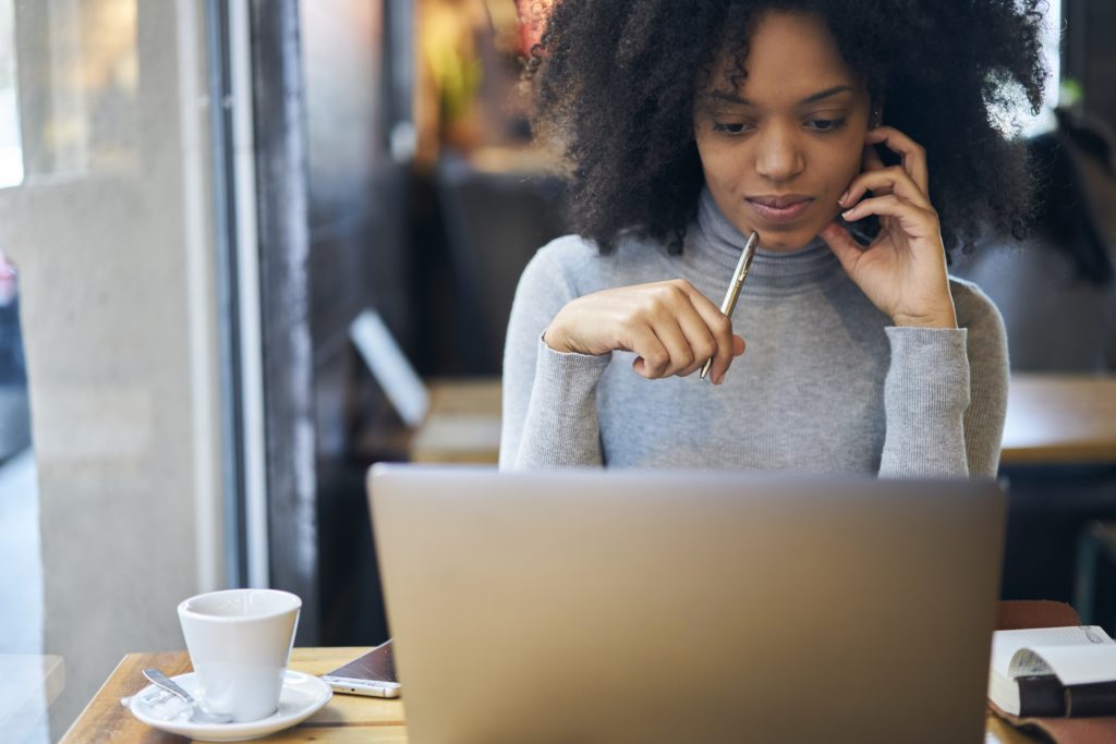 Confident young female looking at her laptop in a coffee shop