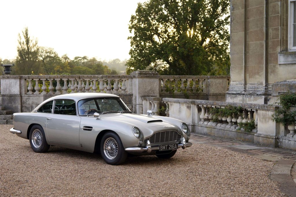 Aston Martin DB5 in white parked outside a manor house on a driveway