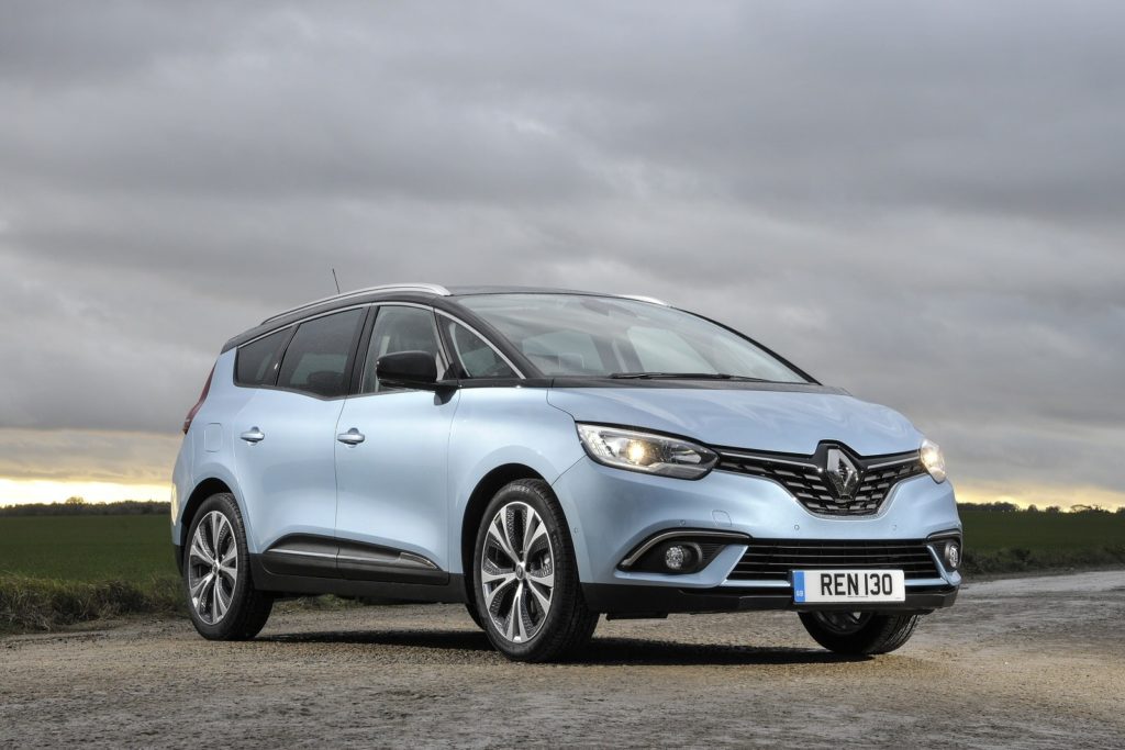 metallic blue renault grand scenic estate parked on gravel with the sun setting in the background