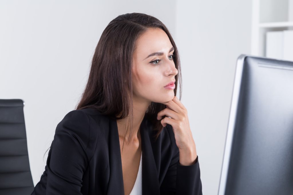 Woman looking at her computer deciding what to do end of lease agreement.