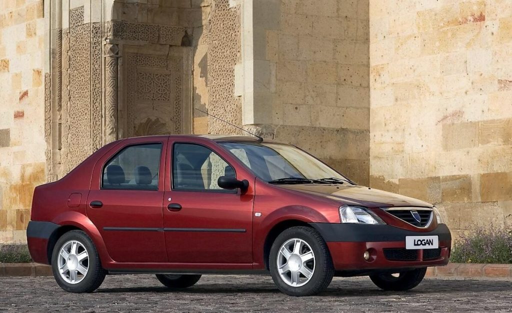 Red Dacia Logan saloon parked outside a building