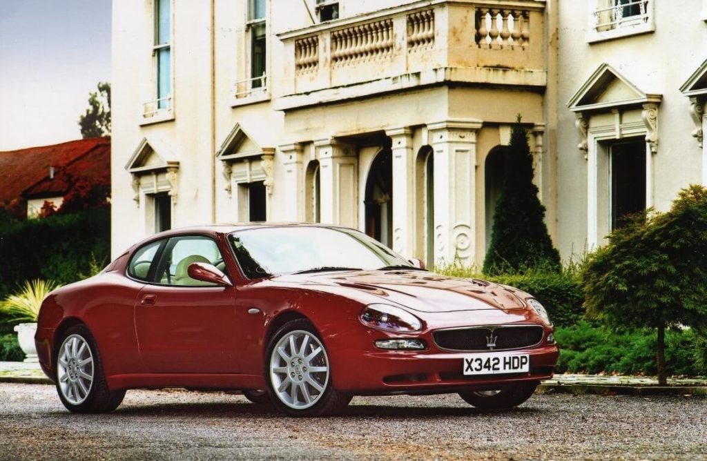 Red Maserati 3200 GT parked outside a manor house