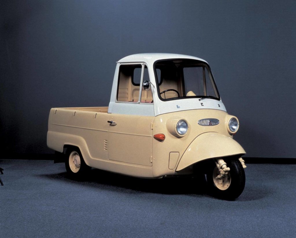 Old yellow three wheeled Mitsubishi vehicle on a blue background