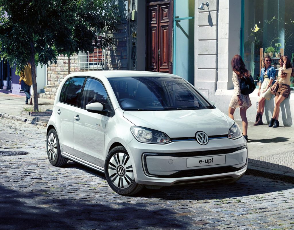 a metallic white volkswagen e-Up! parked in city street