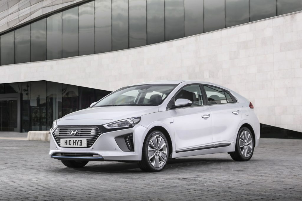 a silver hyundai ioniq electric parked on pavement infront of modern building