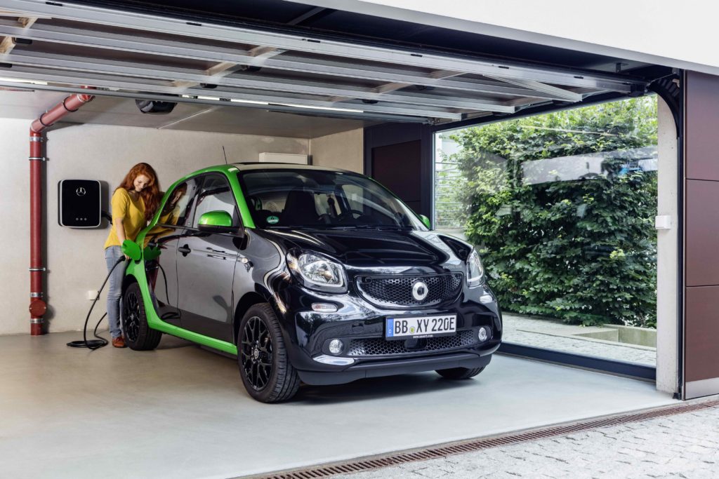 a black and green smart forfour electric drive parked in garage being put on charge